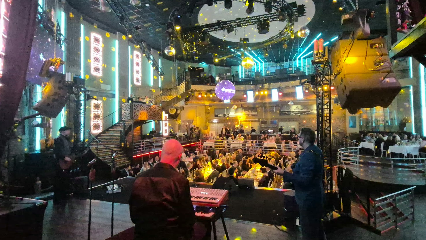 Live band on stage in front of festively laid tables in a club venue